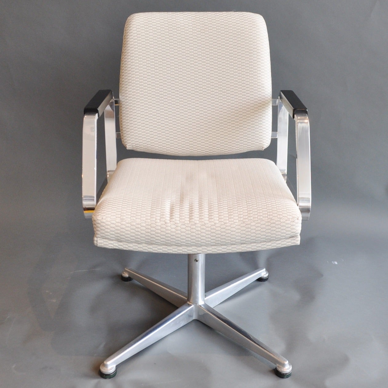 A pair of vintage swivel chairs, beautifully refurbished. The arms are polished chrome with ebony-stained wood arm rests. Each has been newly upholstered in a contemporary fabric to bring them back to their original glory.