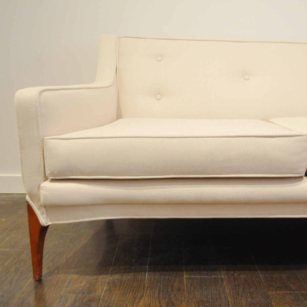 Beautiful example of a 60's era Hollywood Regency 3 seat sofa in newly reupholstered ivory linen.