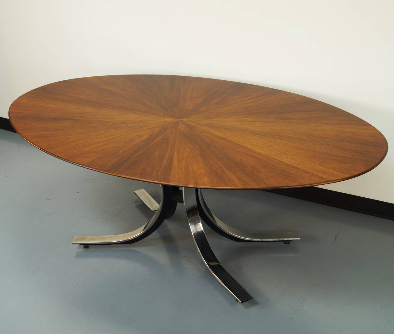 A gorgeous dining table designed by Osvaldo Borsani for Stow Davis. The walnut top veneer features a sophisticated starburst pattern with a stainless steel base. Top has recently been refinished.