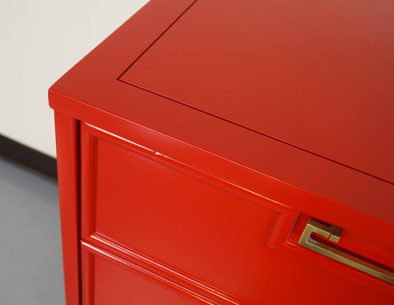 Vintage dresser by American of Martinsville finished in a red lacquered finish with a black base. The handles are made of brass.