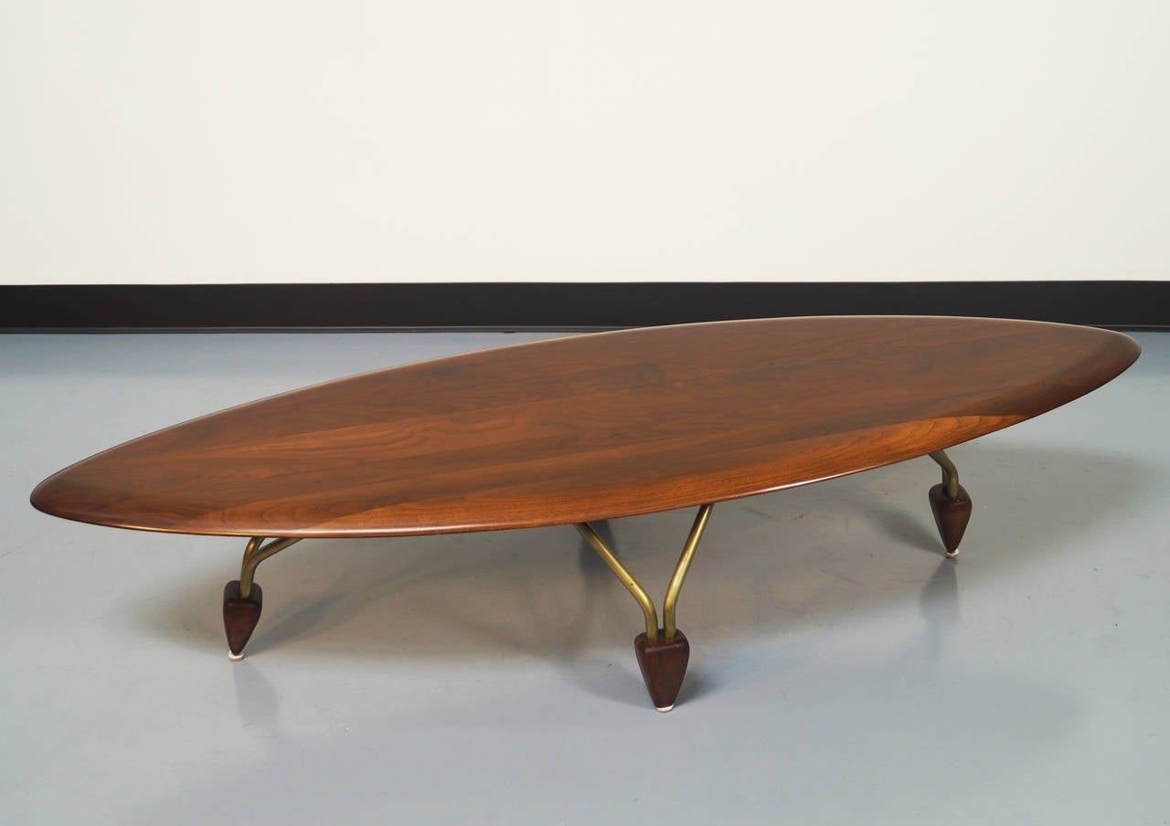 Important surfboard coffee table by John Keal for Brown & Saltman. Beautiful grain with body mounted on brass legs and anchored with wooden feet.

Matching side tables are also available.