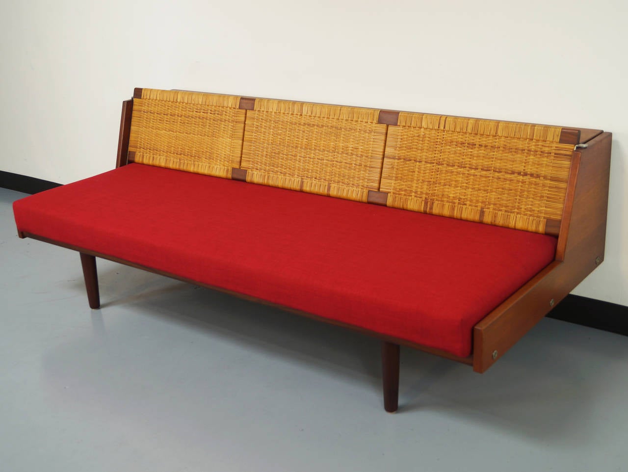 Danish teak sofa or daybed designed by Hans Wegner for GETAMA. Features a teak frame with a cane backrest that lifts up and locks in place to expose a twin bed. Cushion contains original coil springs. Engraved with original designer label.