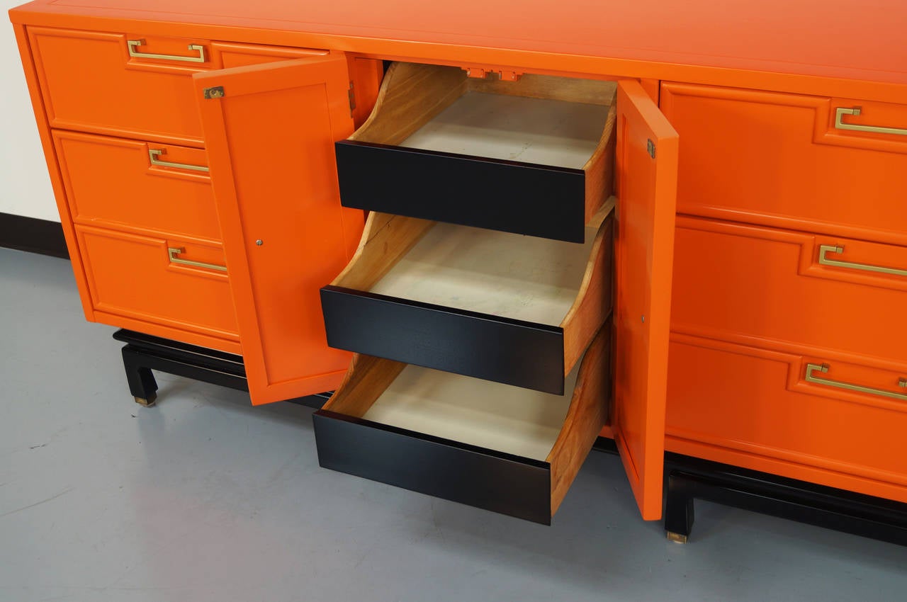 Vintage dresser by American of Martinsville. Refinished in a orange lacquered finish with a black base. Handles are stained in a brass finish.