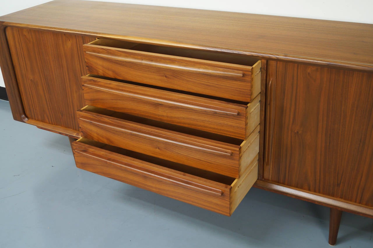 Stunning walnut grain credenza designed by Bernhard Pedersen & Son. This piece features tambour doors with dovetail drawers on each side. The middle section of the piece has a series of four pullout drawers for added storage.