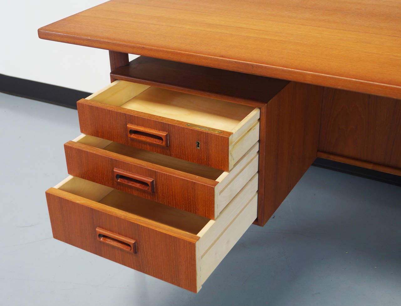 Danish modern floating top desk features three drawers on the left side and one file cabinet to the right. A rear storage space for display.