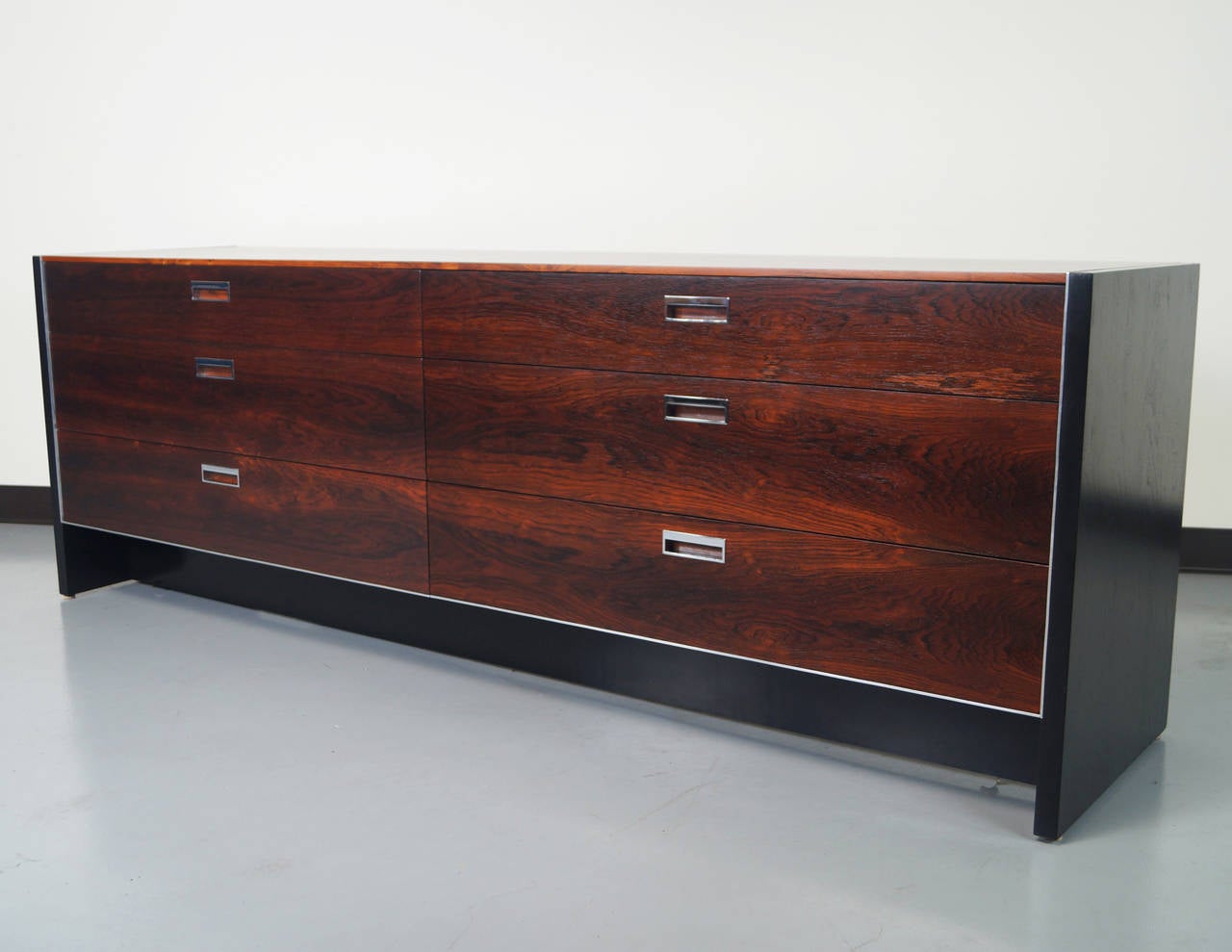 This beautiful rosewood dresser was designed by Robert Baron for Glenn of California. This long rosewood dresser features ebonized sides and chrome hardware and aluminum along the sides.