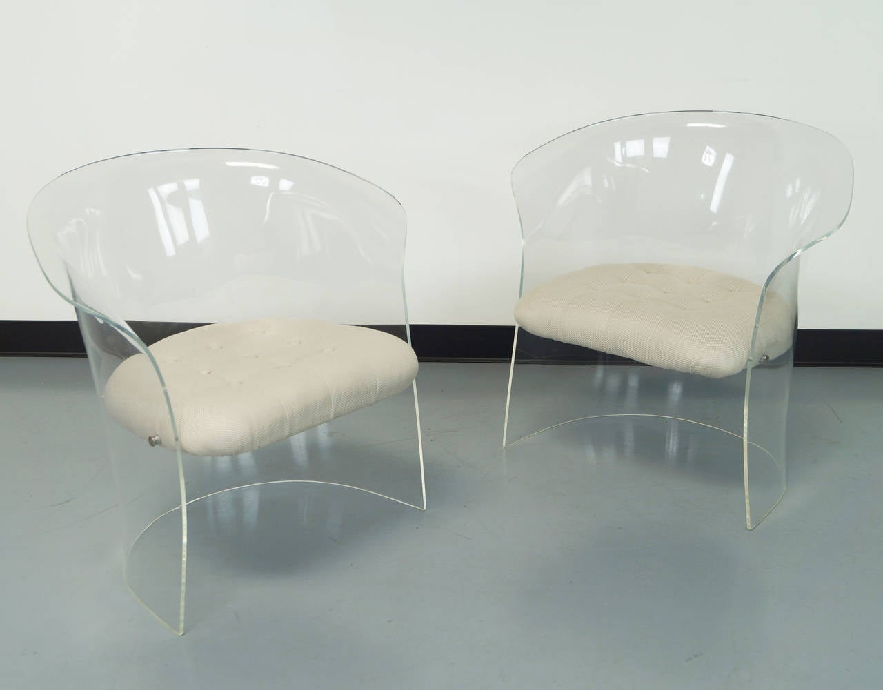 Pair of flexuous Lucite lounge chairs, circa early 1970s. These chairs have curved backs and sides and the seats are attached by chrome covers.