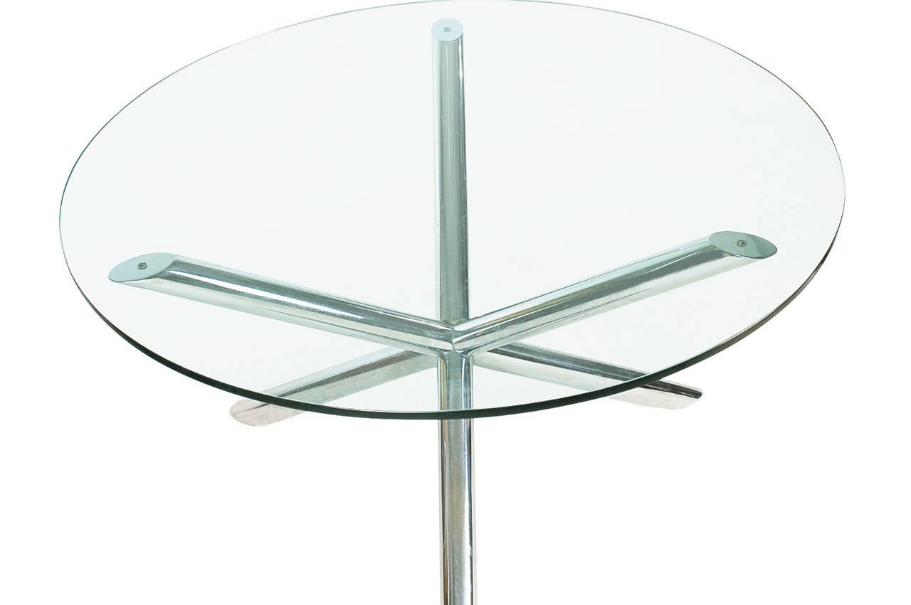 A sleek and stylish glass topped dining table in the manner of Milo Baughman. It features a tubular chrome base with a thick heavy glass top.