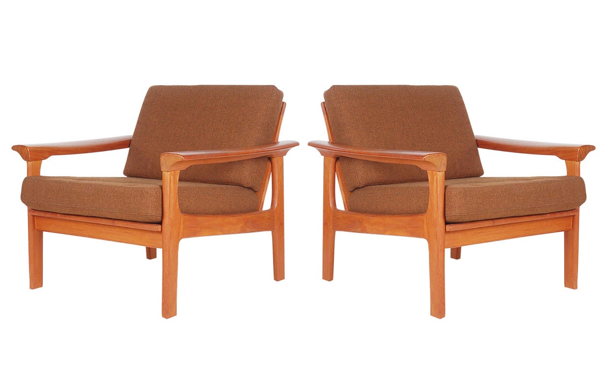 A lovely matching pair of teak lounge chairs. They feature solid teak frames and the original brown tweed upholstery.