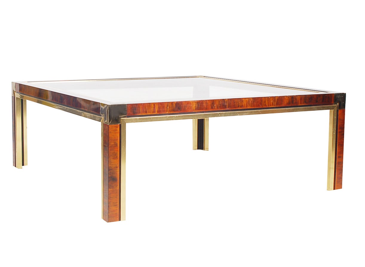 A stunning and rich looking coffee table in the manner of Milo Baughman. It features a tortoise print aluminum base with brass detailing and a glass inlaid top.