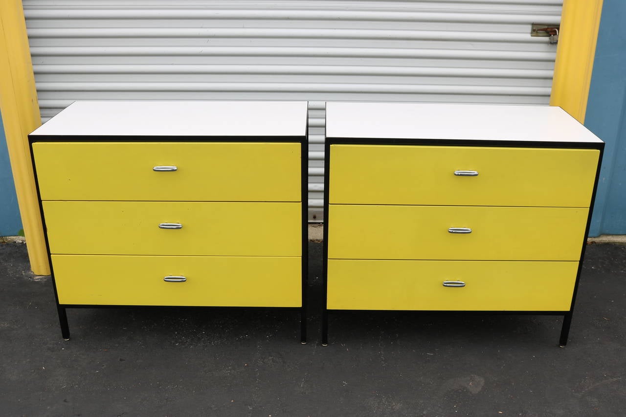 This is an iconic pair of mid century modern chests designed by George Nelson for Herman Miller.  Black frame, yellow drawer fronts and dark green sides and backs.  Sturdy and in very good condition, these chests do exhibit light signs of wear -