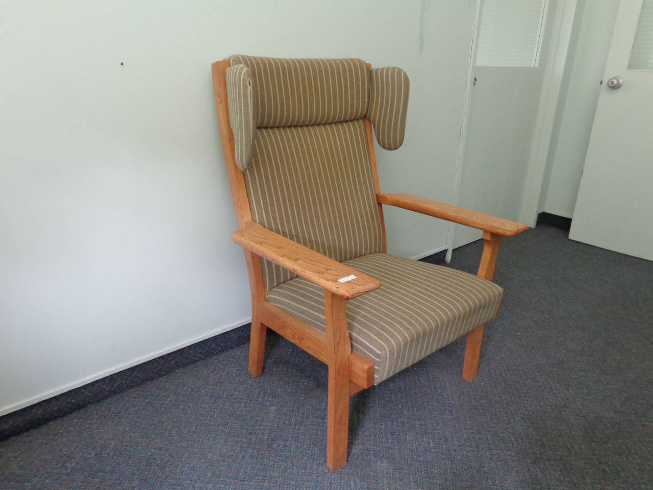 Hans Wegner wing chair frame in lacquered oak with green striped upholstery.