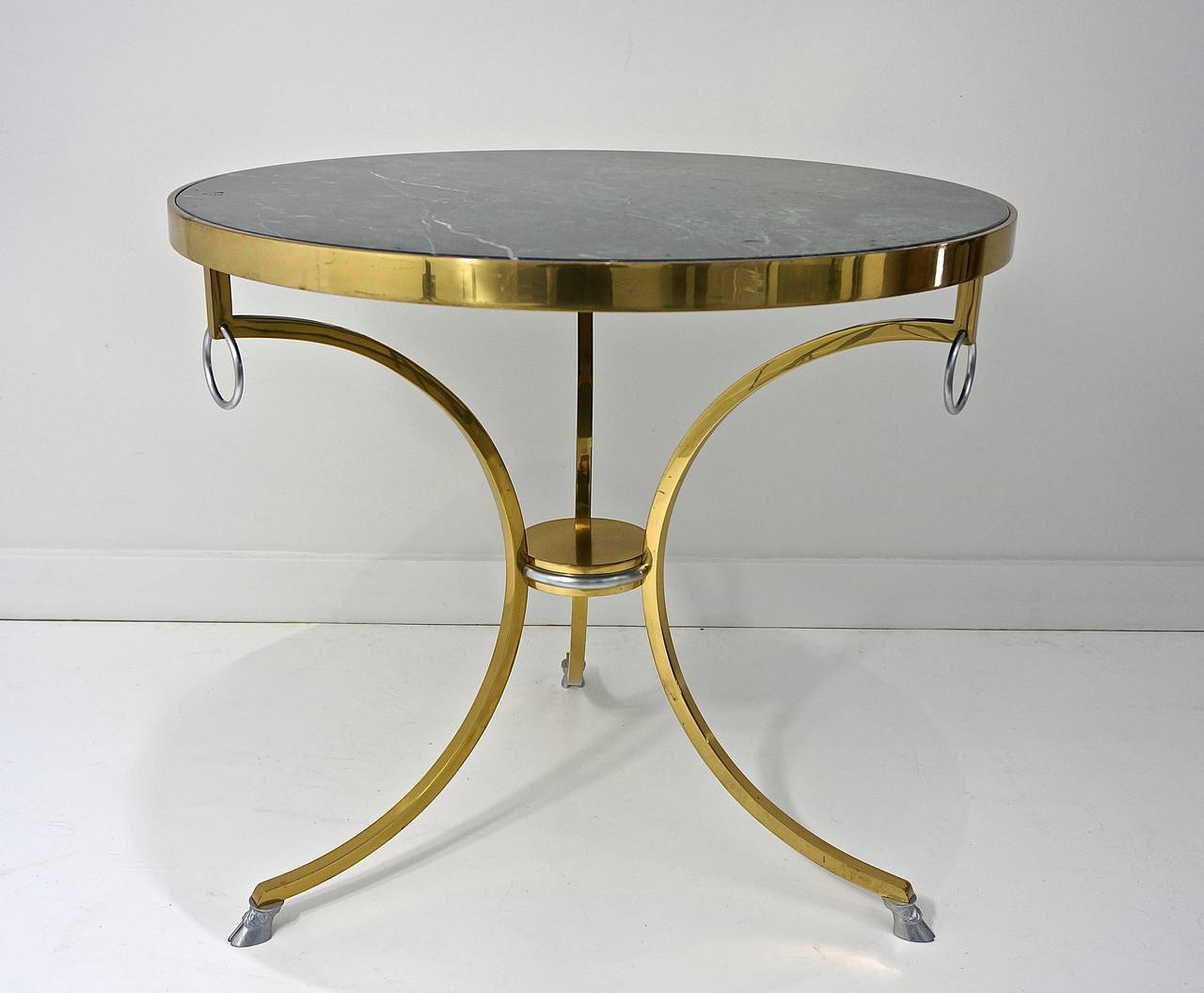 This vintage Neo Classic Italian Gueridon table is beautifully crafted with a polished brass apron and splayed-legs, topped with steel rings and terminating on steel doe hooves. The central support plateau is polished brass with a steel ring band.