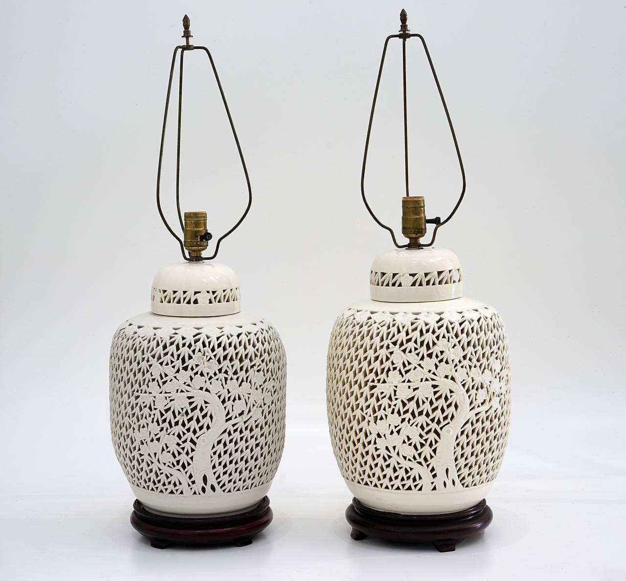 This pair of beautiful 1930's Blanc de Chine lidded ginger-jar's have been converted into table lamps.  These ginger-jars are glazed-ceramic in an off-white coloration, with their original harps.   Each vase is pierced with a motif of