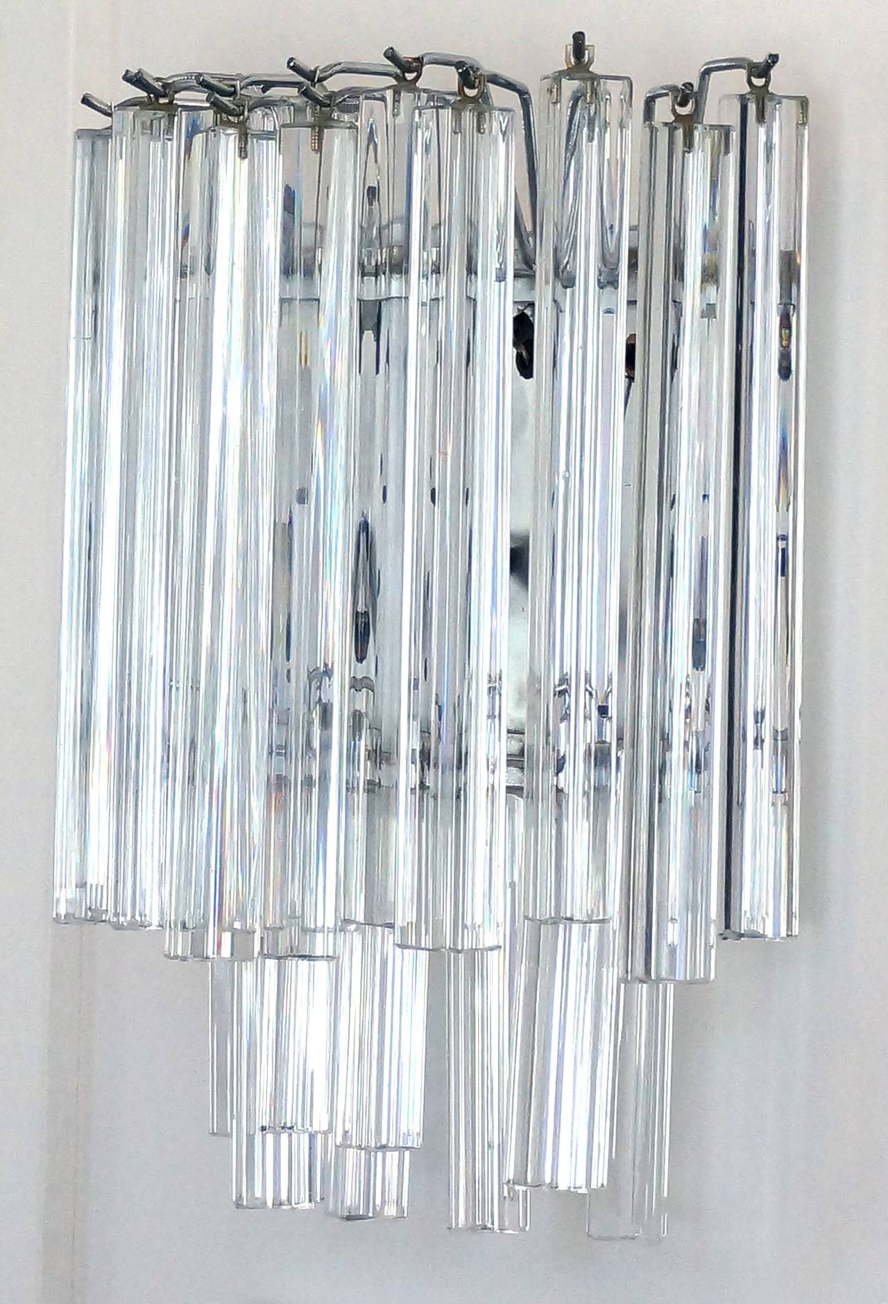 This set of four wall sconces date to the 1960s-1970s, and were produced by Camer Lighting. 

They are composed of two-tiers of three-sided colorless Venini Murano glass prisms. The upper tier prisms are 11