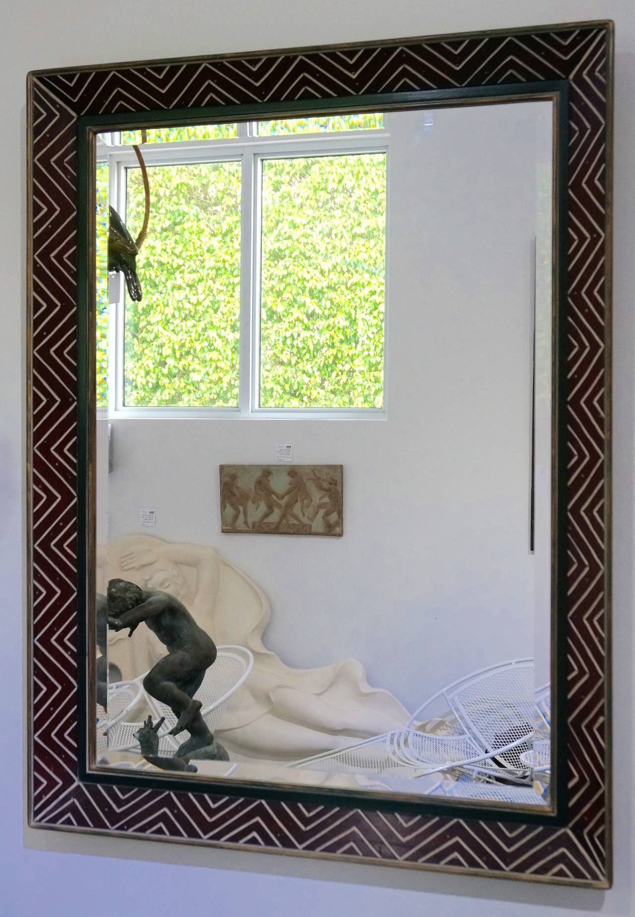 This mirror takes its que from the Art Deco period with its Egyptian-Revival style incised chevron-pattern frame. The frame is painted in soft colors of black, Pompei-red and antique gold.

Please feel free to contact us for a shipping quote, or