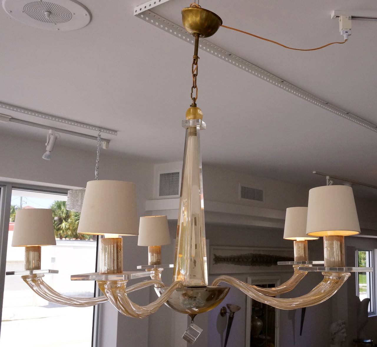 This Murano glass chandelier was created in the 1980s by Seguso for the Angelo Donghia showrooms.  The piece was acquired from the Miami, Florida  estate of the Seguso family.

This piece is done in a clear, champagne and gold coloration.

The
