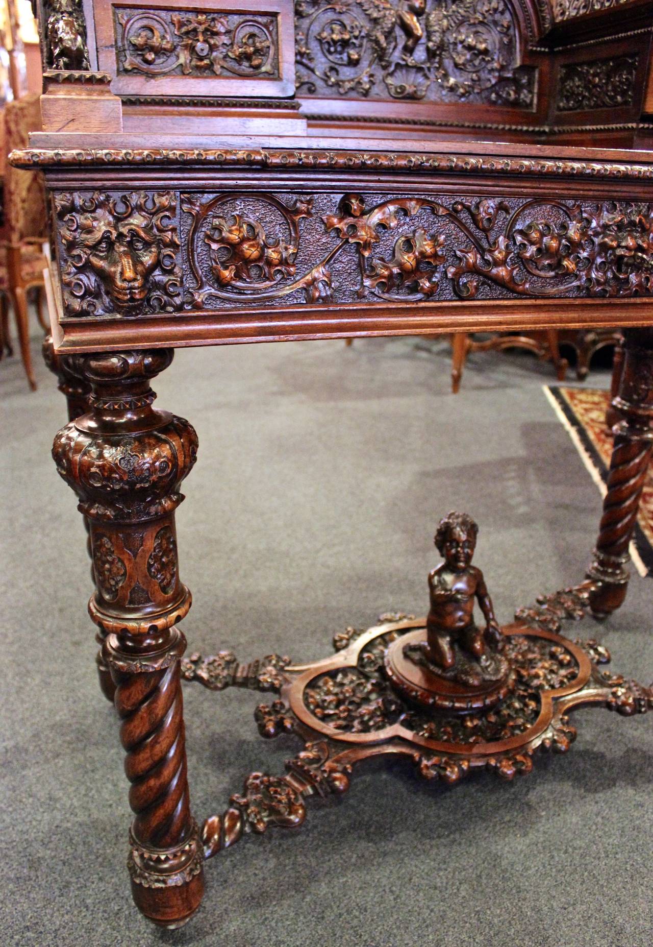 This ornately carved French desk is made from walnut.  The desk features superb carvings of cherubs and accent trimmings that are reminiscent of the Gothic style. Features one large pull out drawer under desk top and two smaller drawers raised above