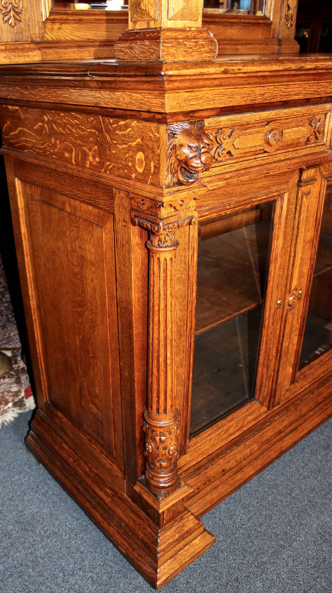 This Belgian cabinet is made in the Renaissance style from oak.  The piece features two mirrored panels and hand-carved detail. Storage for the cabinet includes two pull out drawers, a lower display area with two swing doors, and hanging glassware