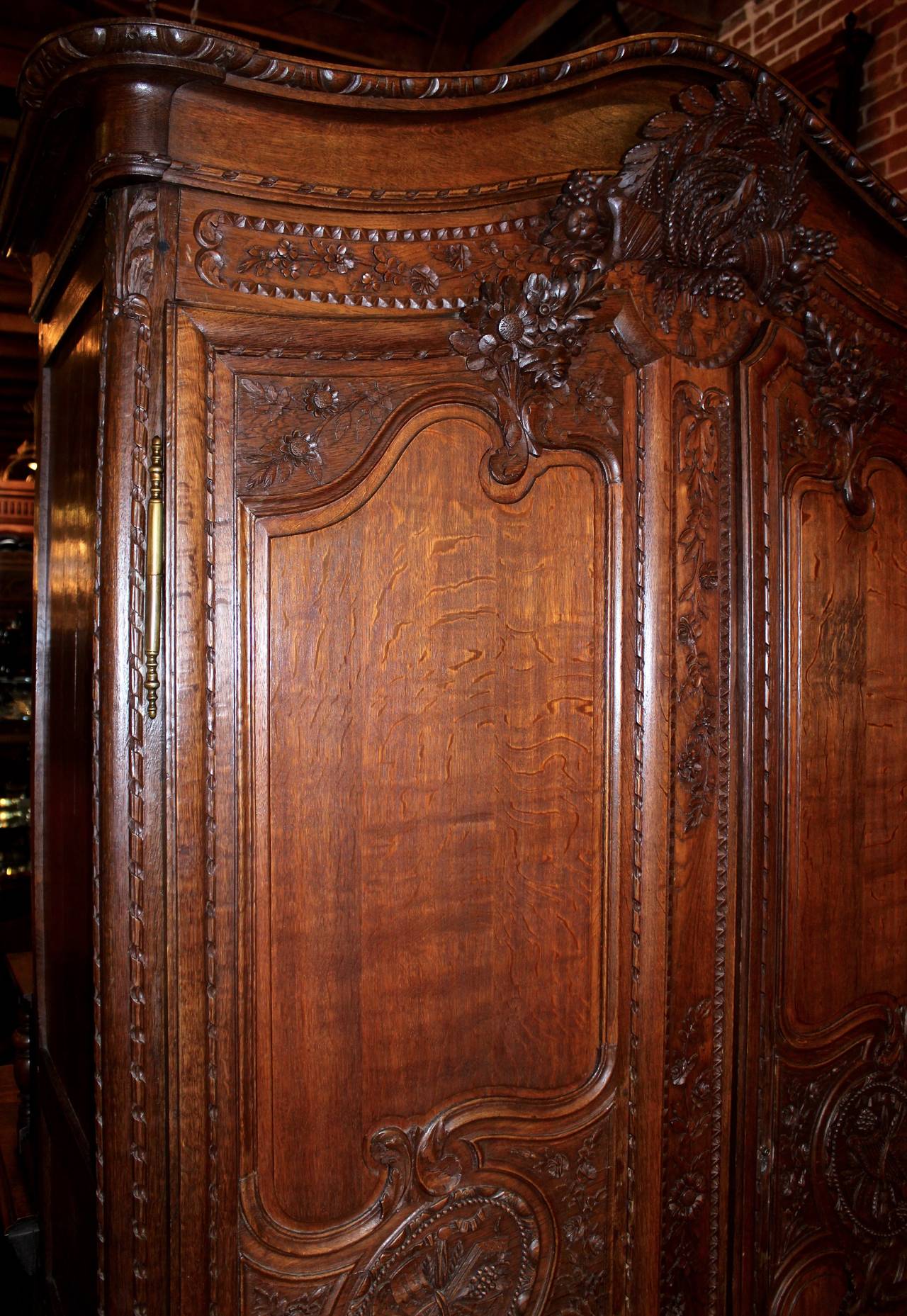 This French Period Armoire is made from oak.  The armoire features gorgeous, hand-carved details along its front and sides.  The two front doors swing open to reveal shelving storage which has been finished to an excellent condition.