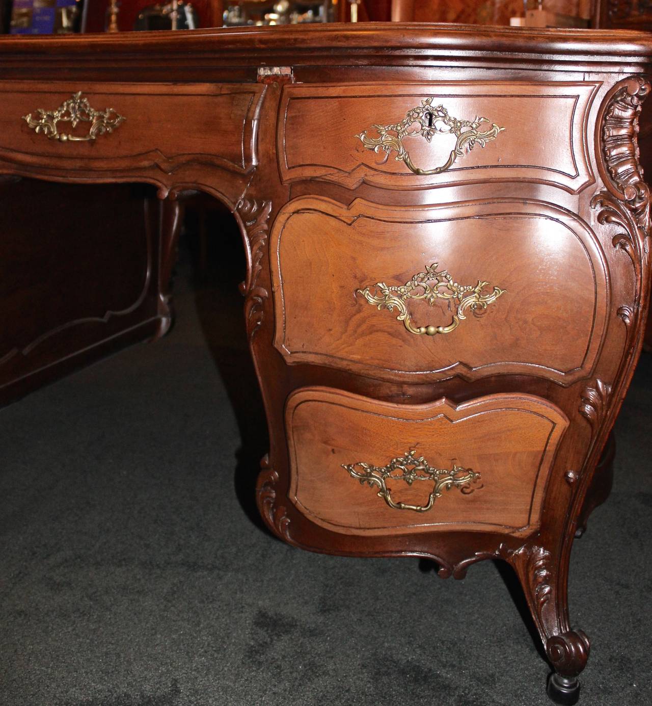 This French partners desk is made in the Louis XV style.  The desk has a bombay shape and features gorgeous, hand-carved details from walnut.  The desk is symmetrical on either side.  Both sides feature four pull out drawers and a large swing door.