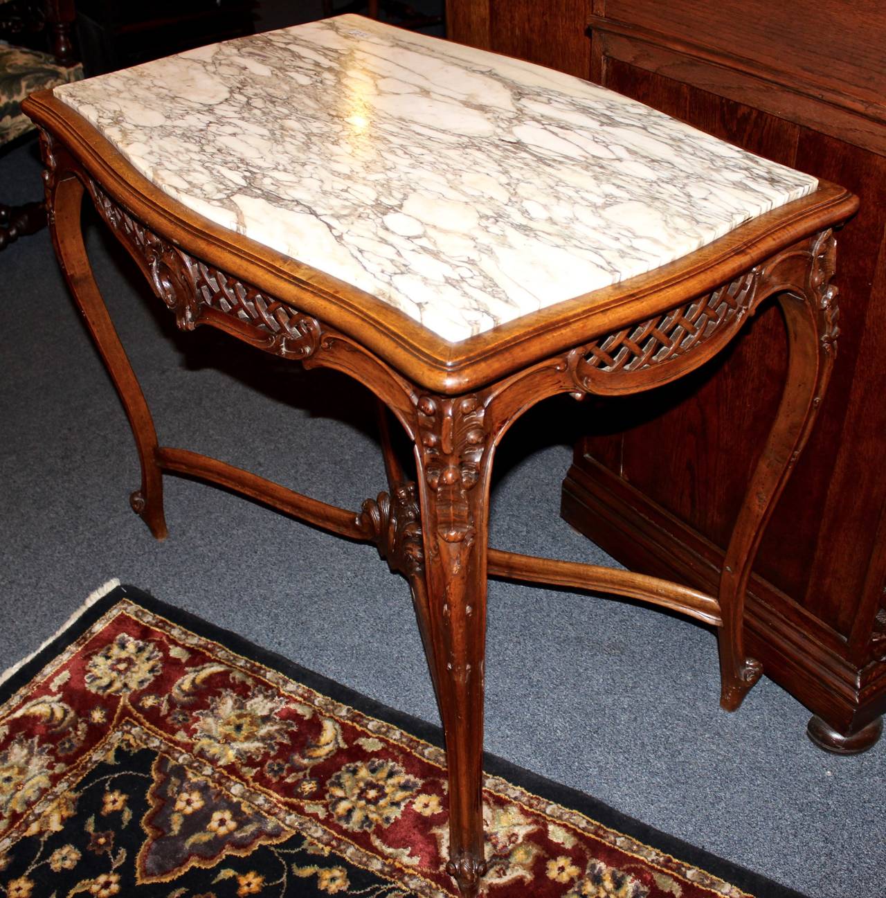 This French library table is made in the Louis XV style from walnut.  The table is adorned with hand-carved detail and is topped with white marble.  The "piercing" technique was used to create a gorgeous crosshatch pattern on each side.