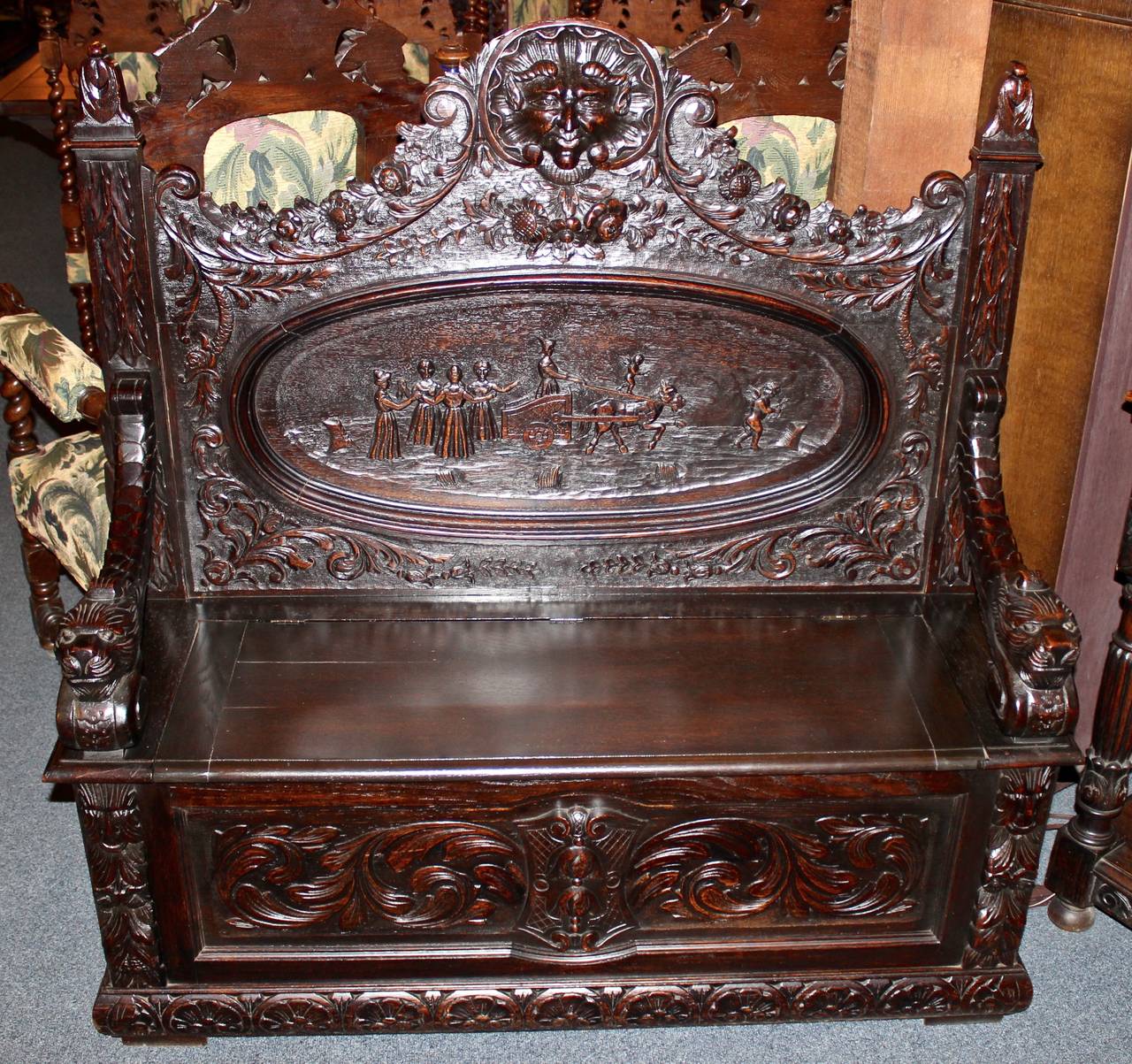 This superbly carved Belgian hall bench is made from oak. The piece features ornately carved details and figural scenes. The seat of the bench opens on hinges to reveal a storage area.