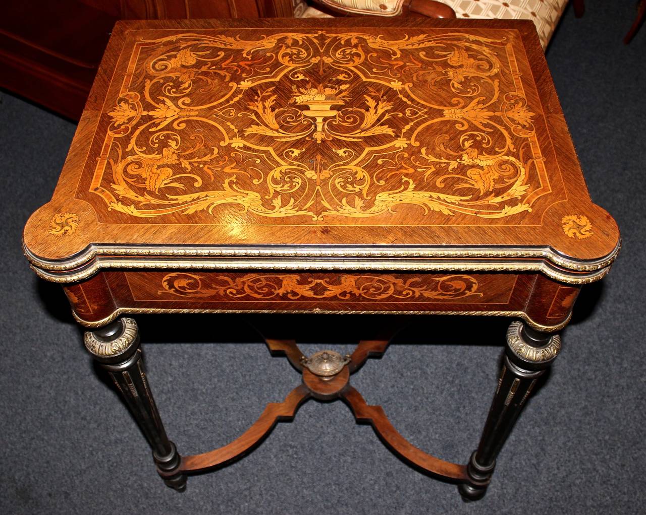 This French game table is made from walnut with gorgeous inlay work.  Extra detail includes ormolu along the sides and down the legs. The top swivels to the side and then folds open to reveal a green felt top.  This movement also reveals the storage