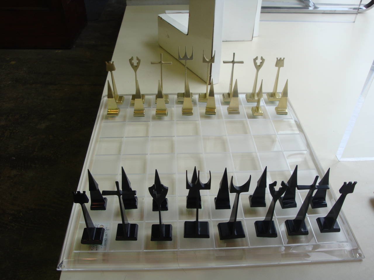 This is a set of aluminum chess pieces designed in 1962 for Austin Enterprises and a newly made lucite board