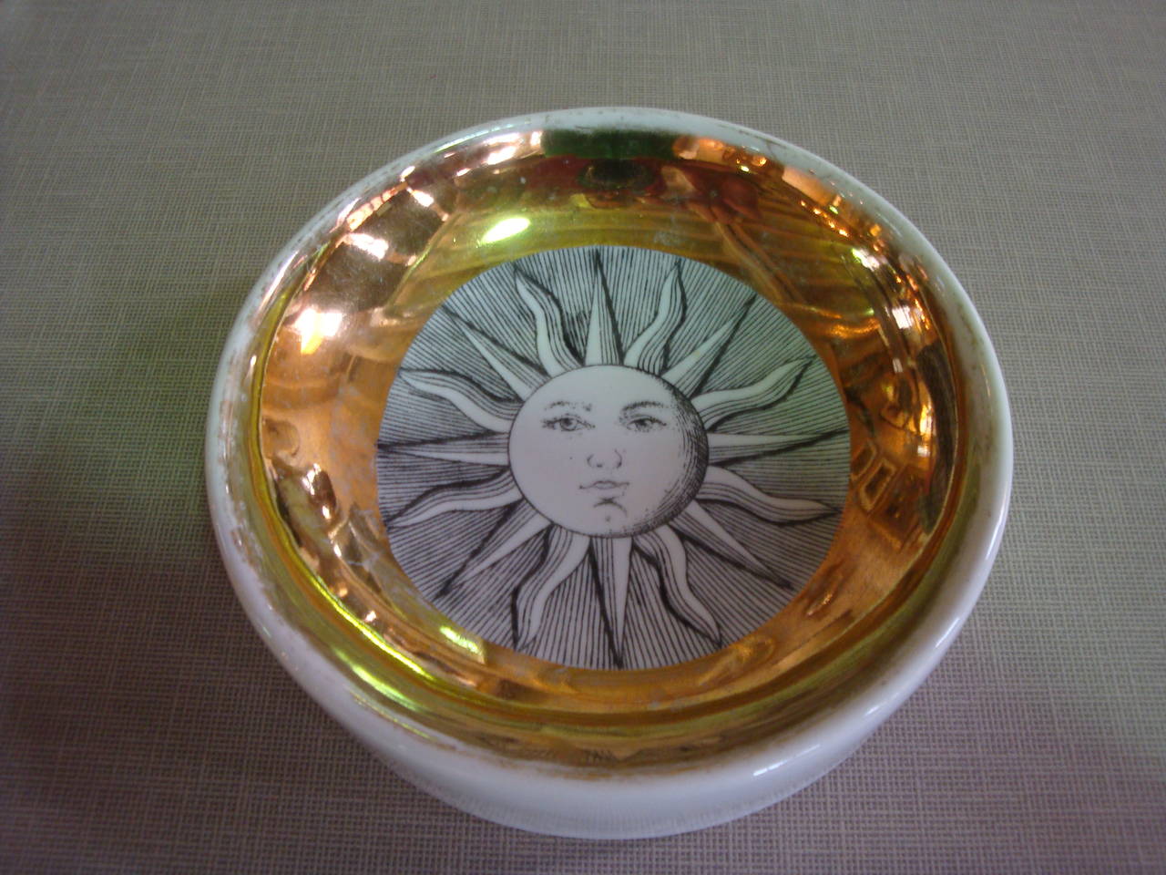 This is a fornasetti Soli e lune dish from 1950s and the padlock paperweight