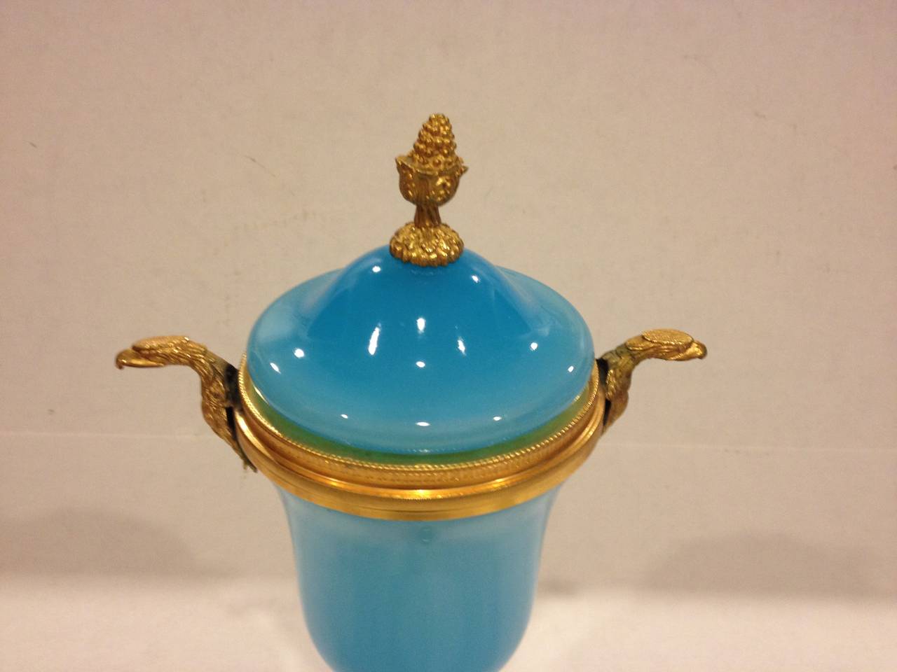 French blue opaline glass lidded urn with gilt metal mounts. Gilt metal acorn finial on lid and eagle handles