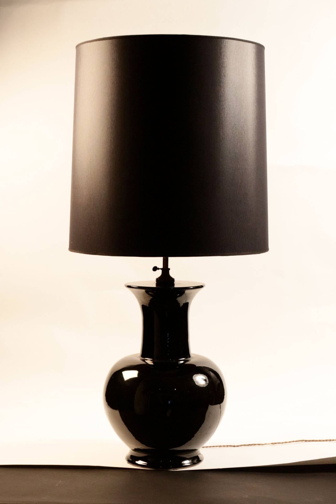 Black enameled ceramic table lamp. Surmounted by and adjustable brass rod with a black cotton lampshade redone according to the original. 
Perfect condition.
Height: 110cm
Diameter: 36cm