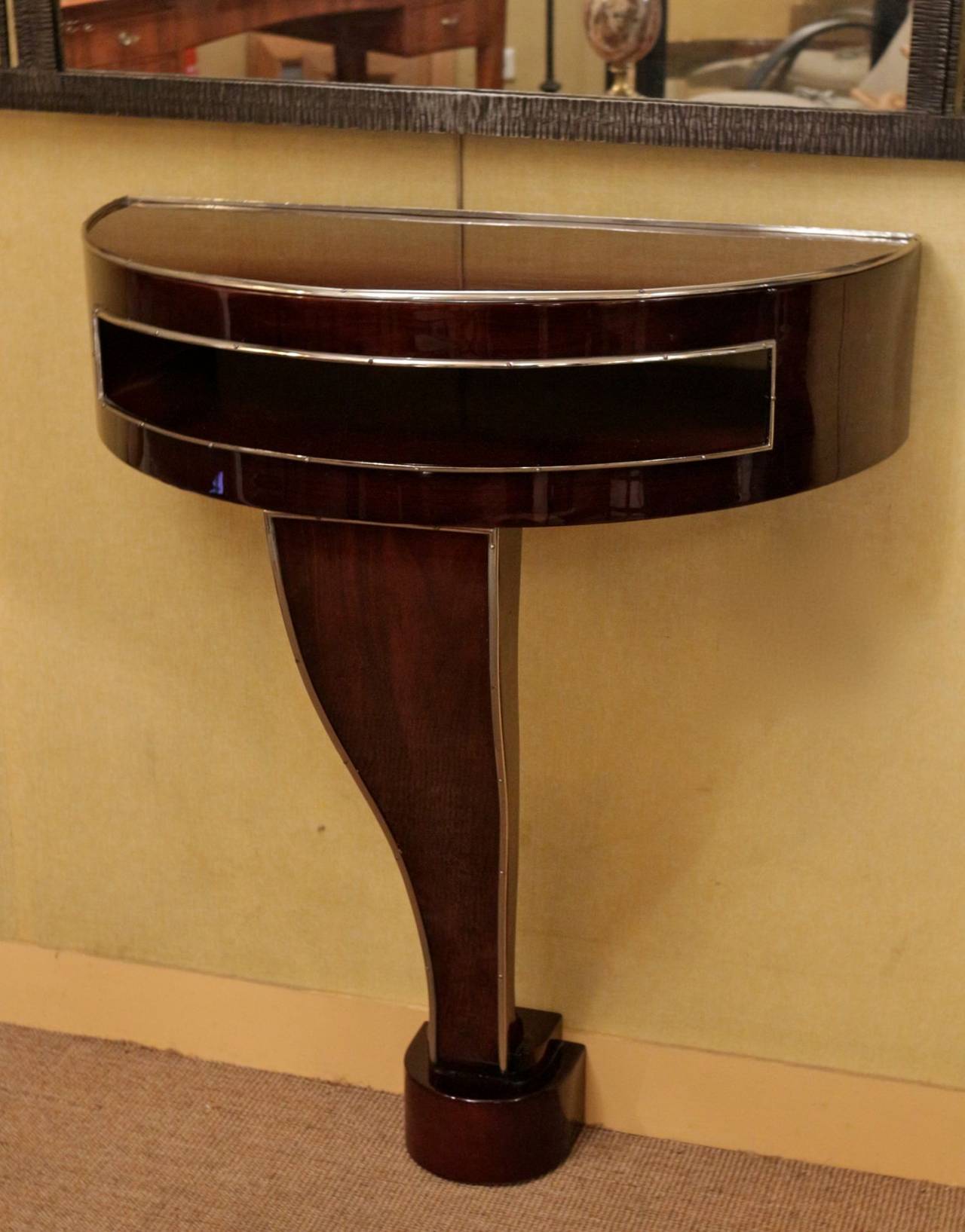 Art deco rosewood console. Half-moon top opened on its middle. The console stands on a curved foot resting on a base. Nickel plated wands enhance the console shape.