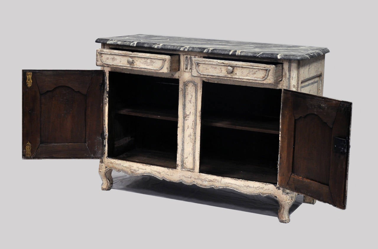 A Classic Louis XV style buffet dating to the 19th century with beautifully painted faux marble top. The body of the buffet features a distressed, multi layered paint finish complete with two doors, two drawers and original hardware. 

Established