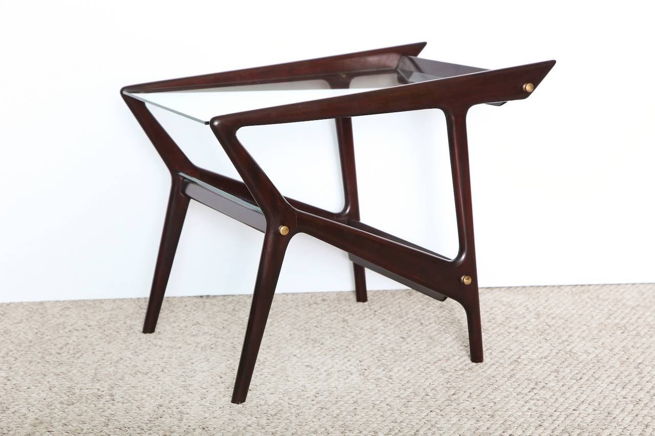 Beautiful, angular side tables with asymmetrical lines in dark stained wood. Each with two glass surfaces and brass mounts. Great graphic forms. These tables are priced individually and a pair is available.