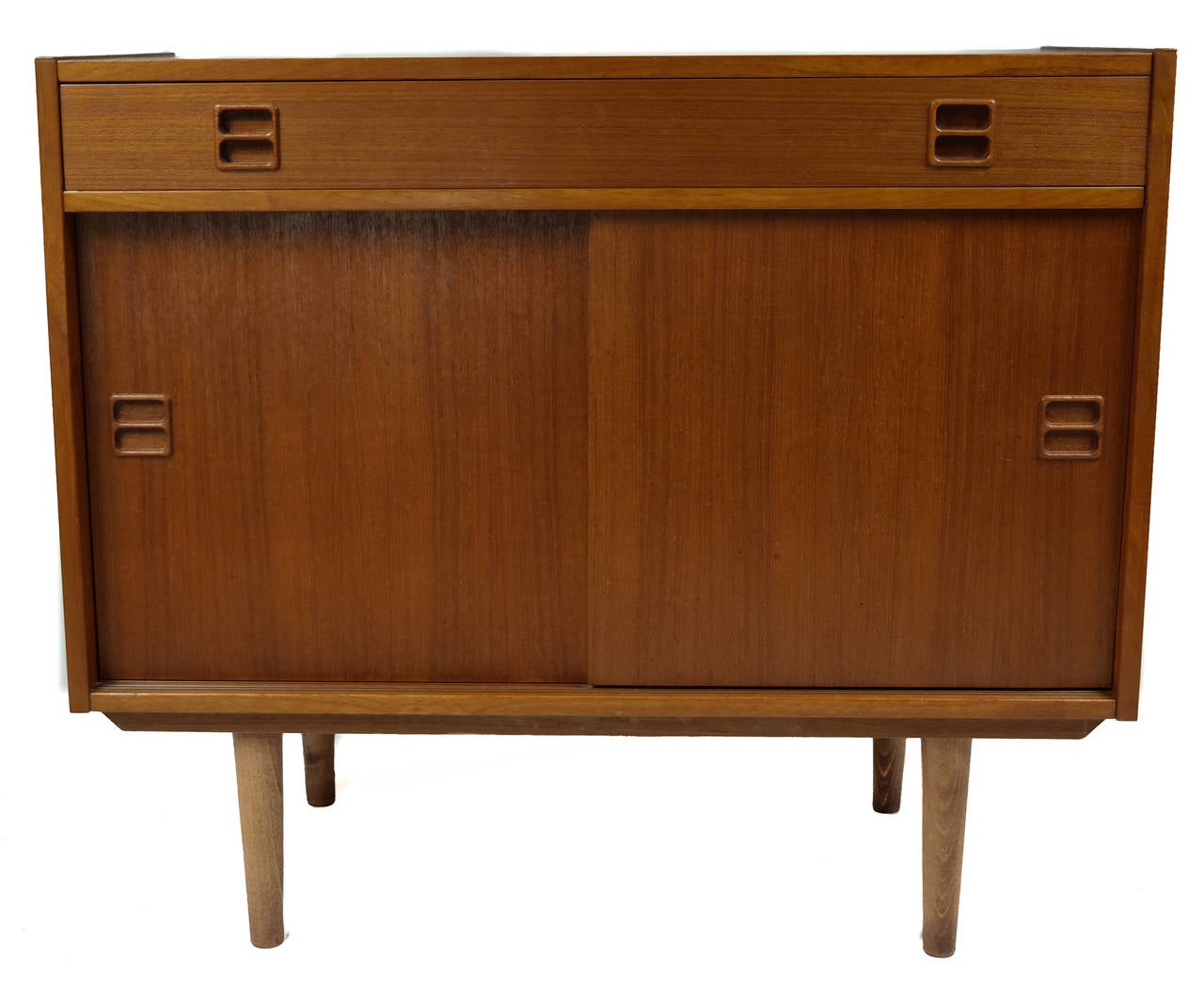 Danish Mid-Century Modern teak wood server, circa 1950s. Features a single drawer over two sliding doors, rising on turned tapered legs.