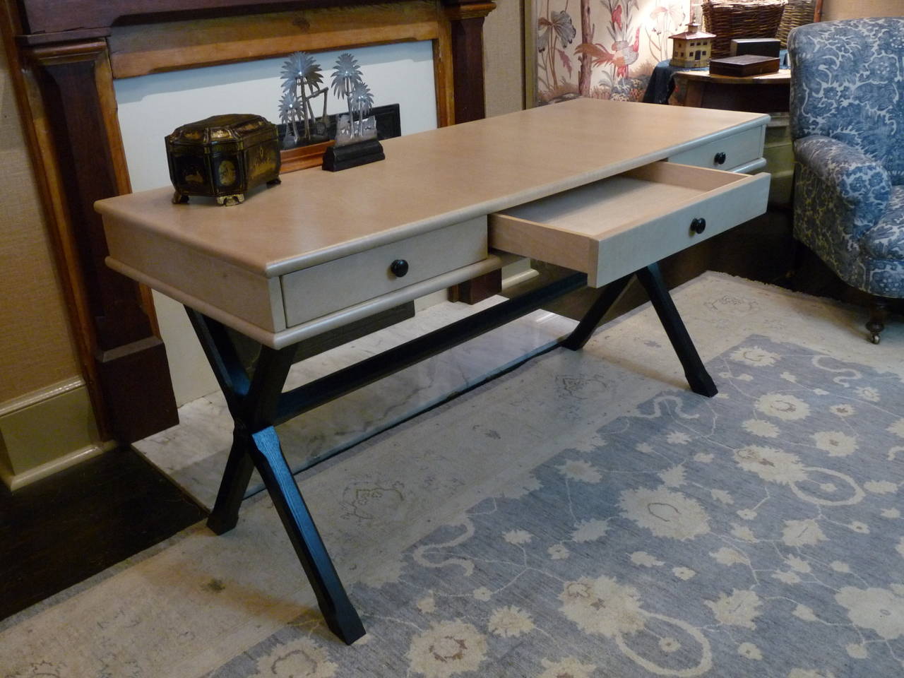 This elegant desk is handmade exclusively for The Outpost in England. It is very solidly constructed with select hardwoods and features three silent-close drawers. The X-frame base is chamfered and ebonized and the desktop is wrapped in luscious