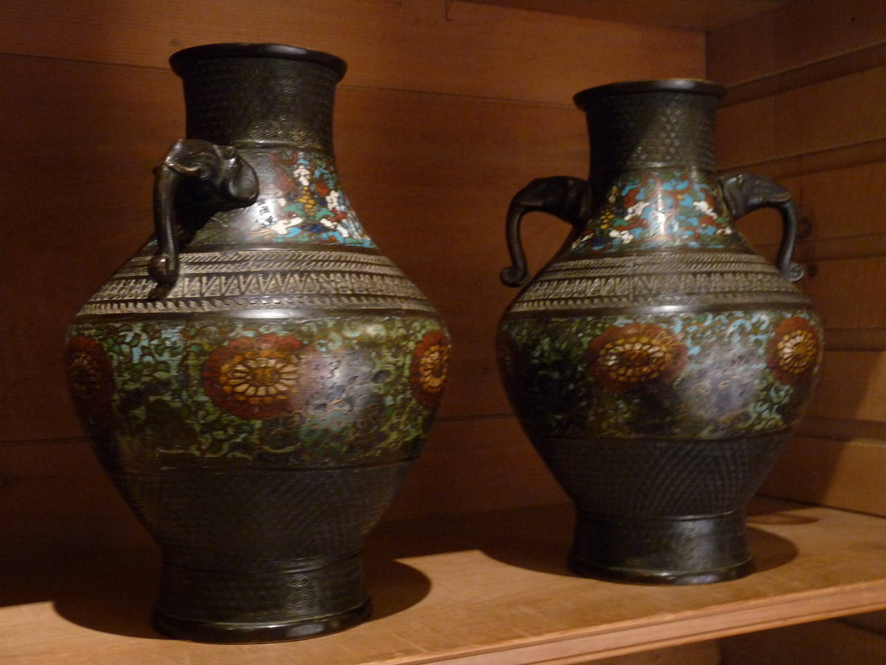 A beautiful pair of Cloisonné bronze vases with stylized elephant head handles. 
The enamel has wonderful detail and color making the vases a striking pair.