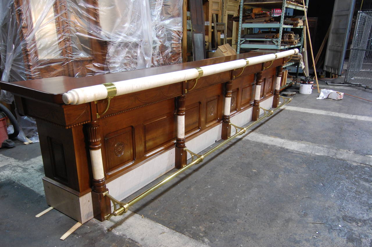 Perfectly re-finished early mahogany front bar with marble columns and armrest, probably from a tavern or fine dining establishment. All polished brass original fittings, with hand-carved elements throughout. A rare early piece, unusual for both its