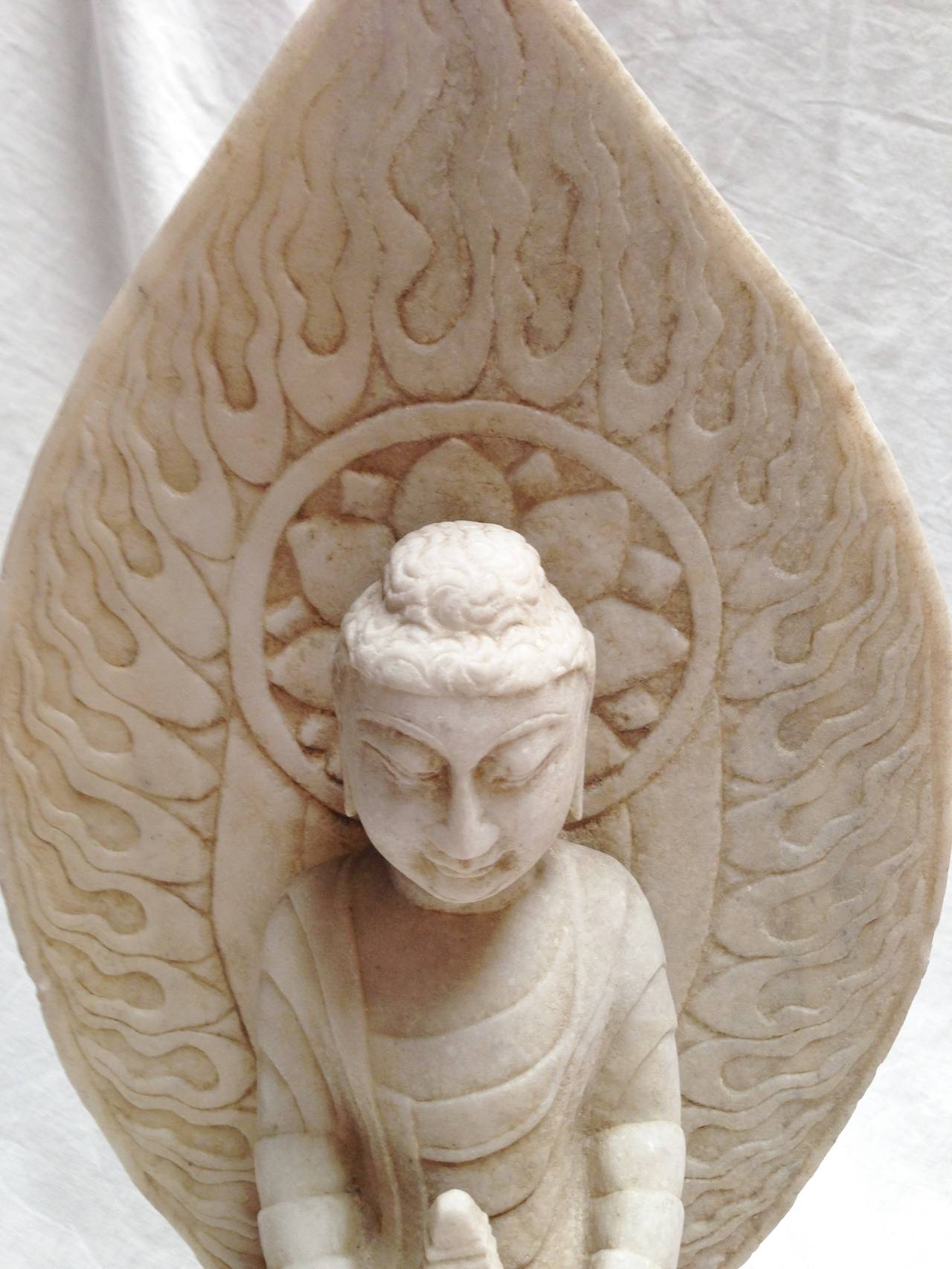 Beautiful Buddha is hand carved from solid marble. Fantastic fire halo is the highlight of this wonderful piece. Buddha is seated on lotus throne, holds a pagoda in his hands symbolizing peace and faith.