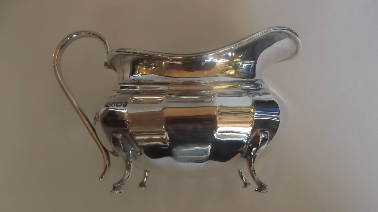 A four-piece paneled side bulbous sterling silver tea service with bone insulators and finials. The rounded bottoms allow for a full pot of coffee or tea. Complete with an open sugar and creamer. This set was made in England, in the city of