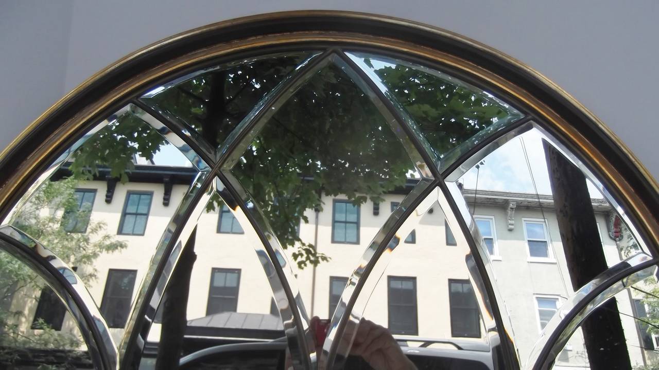 An Italian made wood and metal framed mirror.
Well made arched top mirror with separate beveled glass components with a gilt and wood toned frame.  The shape and size are the size of a standard window and give the impression and light of having a