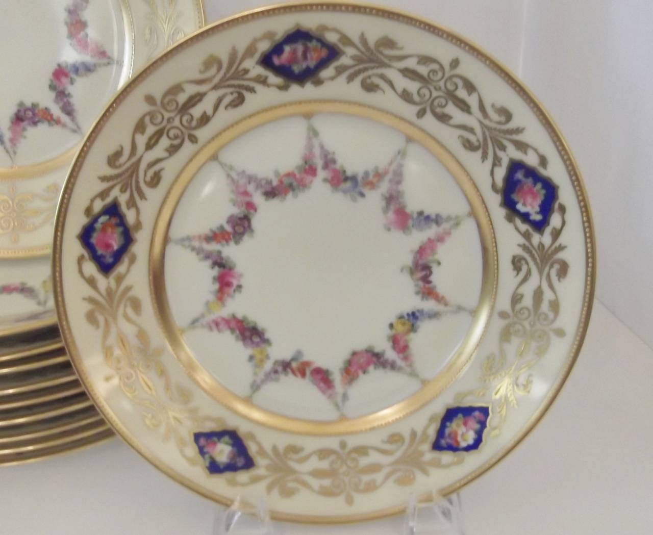 Twelve delicately painted accent plates made by Dresden.
Raised gilt borders with cobalt cartouches with floral centers. Inner and outer gold bands with raised beading with hand painted garlands of flowers in the centers. Image 8 and 9 show these