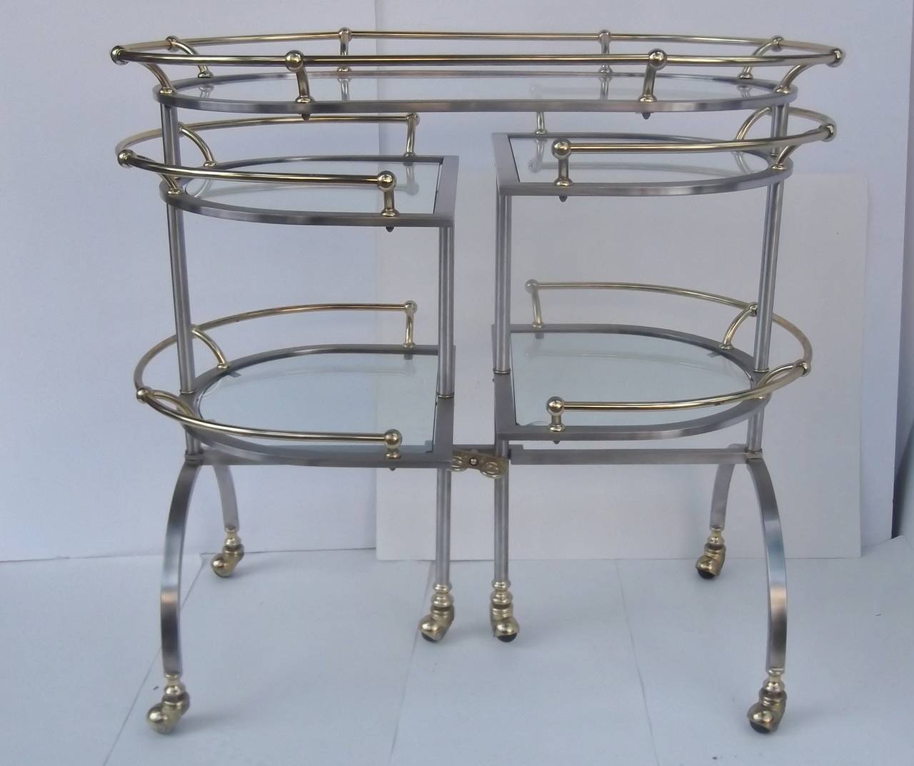 Very unique bar cart with roll out sides.
Triple tiered with brass gallery edge, the sides swing out on castors to offer a doubled serving area.  The tiers on each side are slightly lower on one than the other.  A total of six castors support this