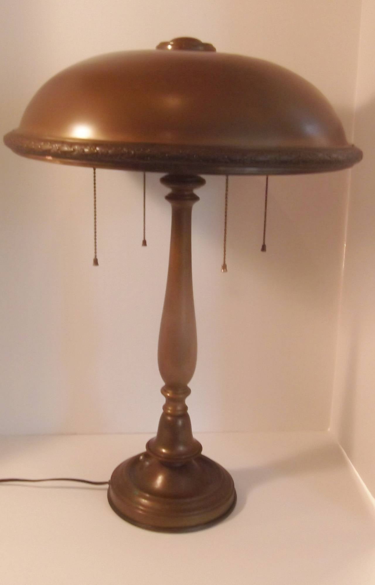 This is a early 1900's solid brass, original patination table lamp.
Newly re-wired with original 4 arm socket fixture for ample light
with both individual pull chain on/off switches and one on/off 
switch at base of lamp. Trim along bottom of