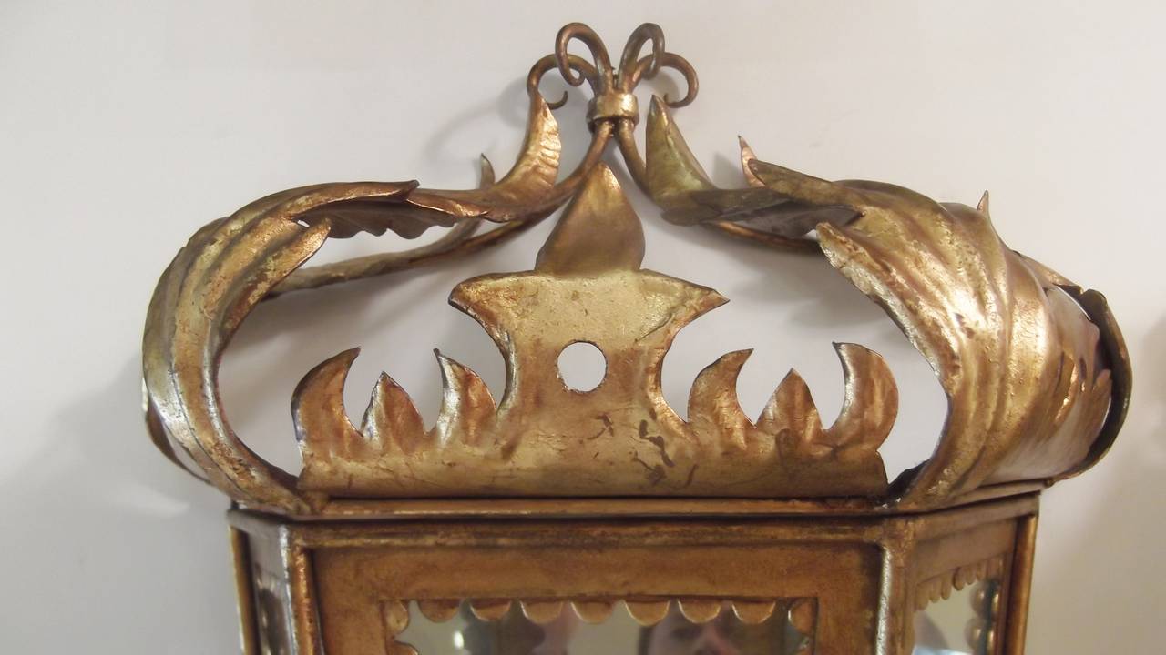Whimsical Italian gilt toleware sconces with mirrored backs. Beautiful foliate design with glass panel front and sides. The top lifts off to assist with changing the bulb. Scalloped detail around the glass panels. These can be plugged in or have an
