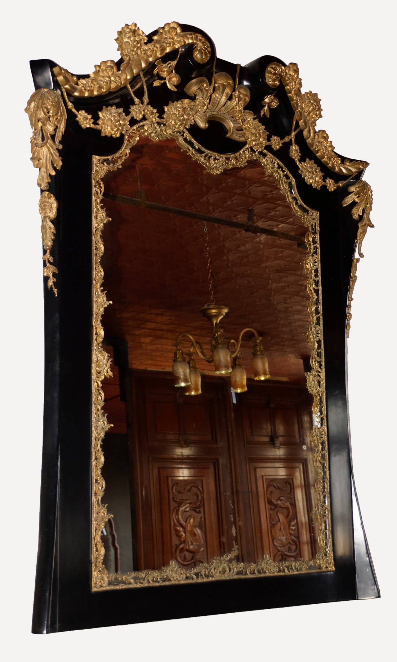 Elegant circa 1900 Georgian Revival style black lacquered overmantel mirror surmounted by swan neck pediment with ormolu mounts. Mirror plate has undulating top with pierced ormolu crest and is surrounded by finely detailed rocaille metalwork.