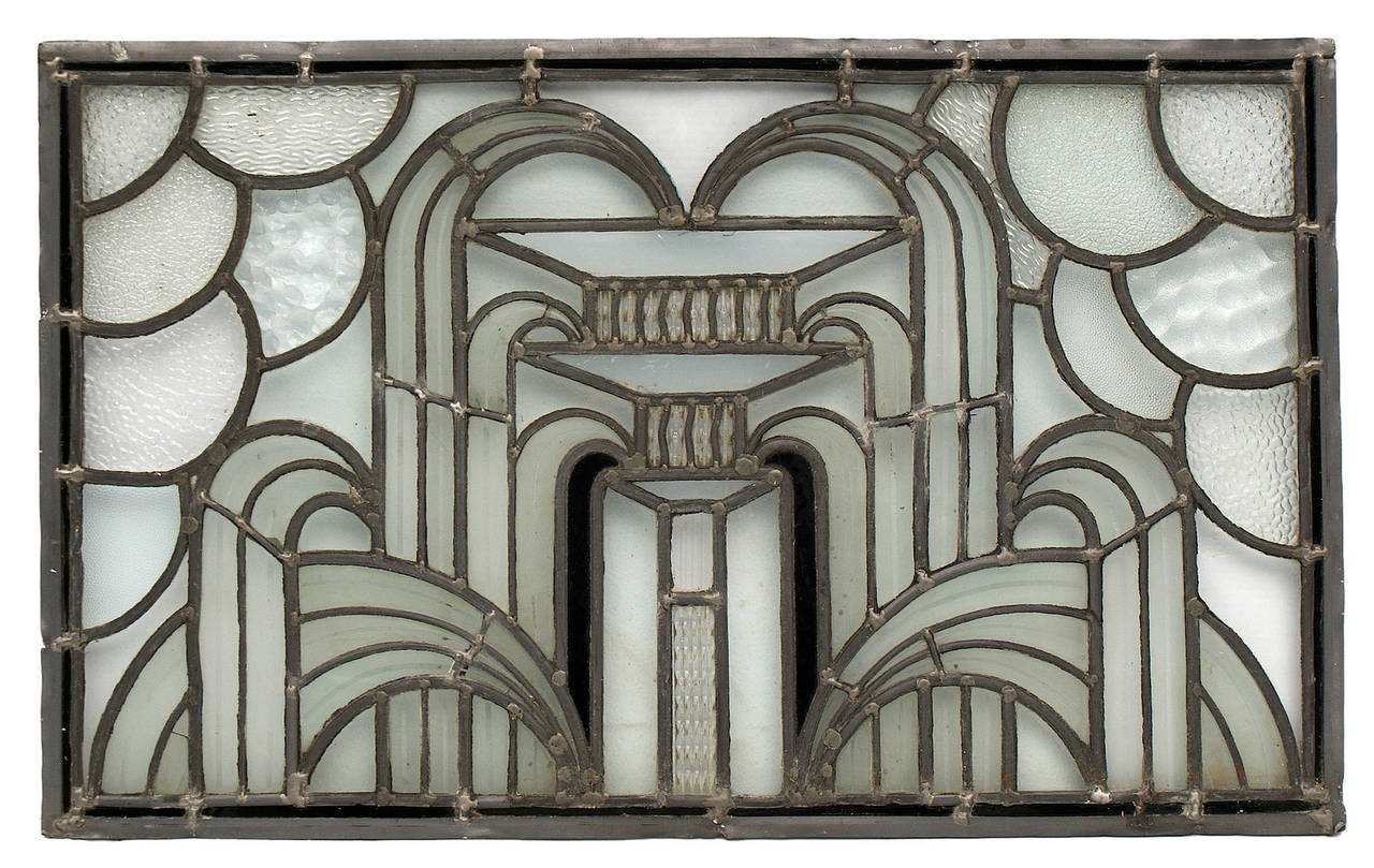 Very fine Art Deco style leaded glass window having fish scale pattern and central stylized fountain motif. Textured glass panes are of varying patterns. The window is secured in a temporary wood frame.