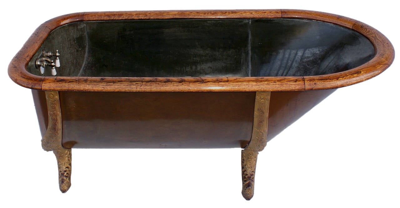 Beautiful antique copper bathtub with cast iron legs and an oak frame top.
