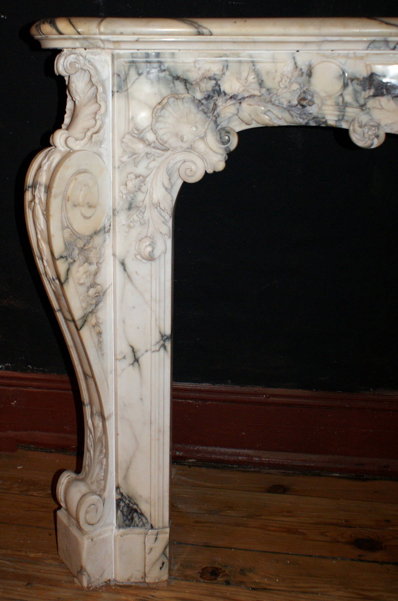 French, circa 1740, Louis XV Italian Pavonazzo marble fireplace mantel having canted, corbel form jambs on block feet. Serpentine form, paneled lintel is elegantly carved with scrolling foliate and shell motifs and has a bouquet form keystone with